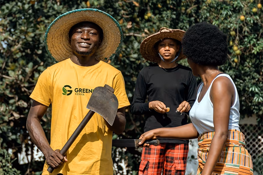 Green Leaf Kenya team member holding a hoe, with two young women in a garden